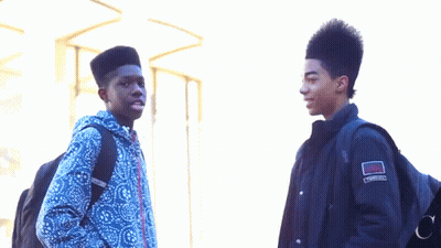 Two Young Men Standing Next To Each Other With One Wearing A Jacket That Has The Word Converse On It GIF