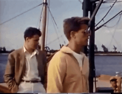 Two Young Men Standing On A Boat GIF