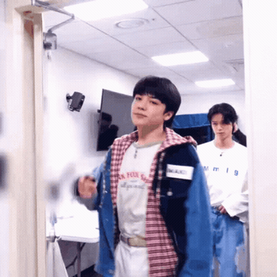 Two Young Men Standing One Wearing NM Shirt GIF