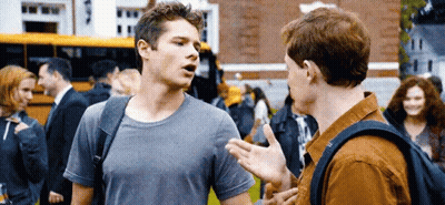 Two Young Men Talking In Front Of School Bus GIF