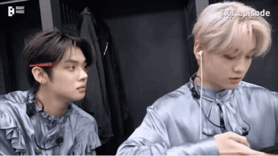 Two Young Men Wearing Earphones Sitting Next To Each Other GIF