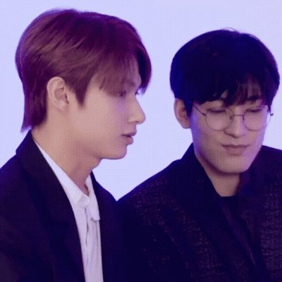Two Young Men Wearing Glasses Are Sitting Next To Each Other And Looking At Something . GIF
