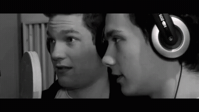 Two Young Men Wearing Headphones Talking In Black And White GIF