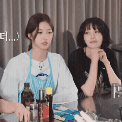 Two Young Women Are Sitting At A Table With Bottles Of Sauces And Condiments GIF