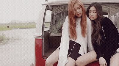 Two Young Women Are Sitting On The Back Of A Red Van . GIF