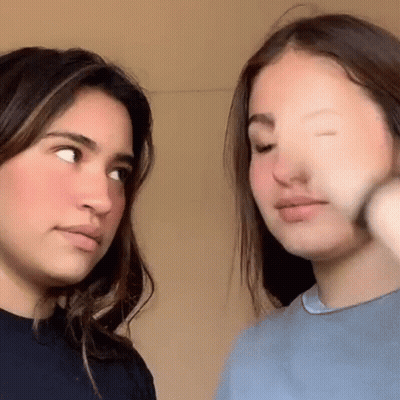 Two Young Women Are Standing Next To Each Other And Looking At Each Other With Their Eyes Closed . GIF
