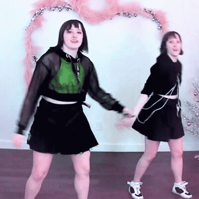 Two Young Women Dancing By Christmas Tree GIF