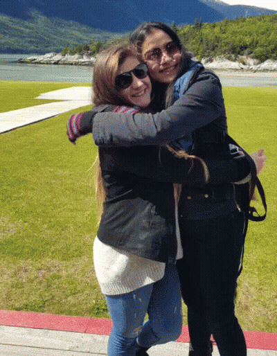 Two Young Women Hugging In Front Of Lake GIF