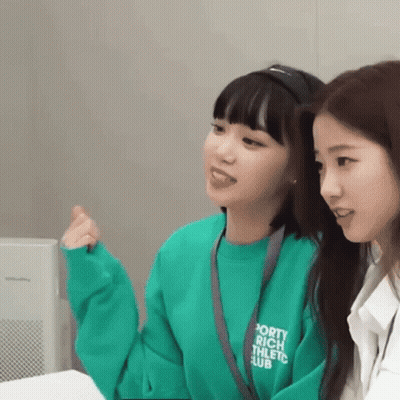 Two Young Women Sitting Next To Each Other One In Green Sweatshirt GIF