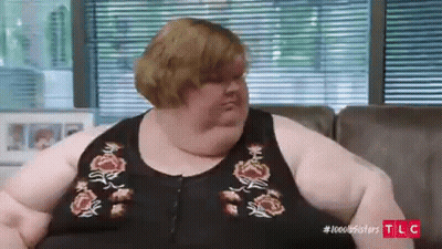 Very Fat Woman Sitting On Couch In Front Of Blinds GIF