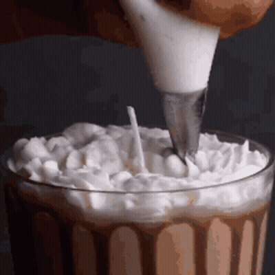 Whipped Cream Is Being Poured Into A Glass With A Piping Bag . GIF