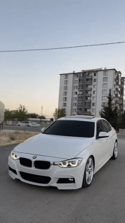 White BMW Parked In Front Of Tall Building GIF