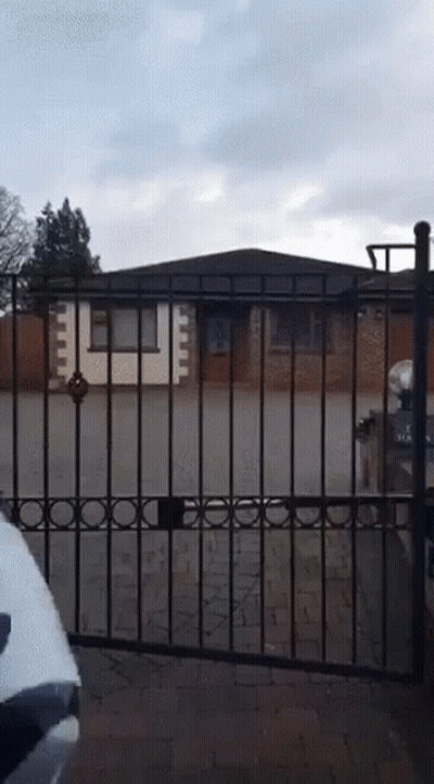 White Car Parked In Front Of Fence And Brick House GIF