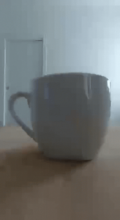 White Coffee Cup On Wooden Table In Front Of Door GIF