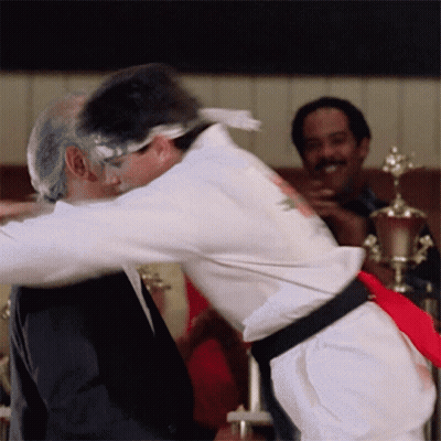 White Karate Uniform Man Hugging Black Suit Man GIF