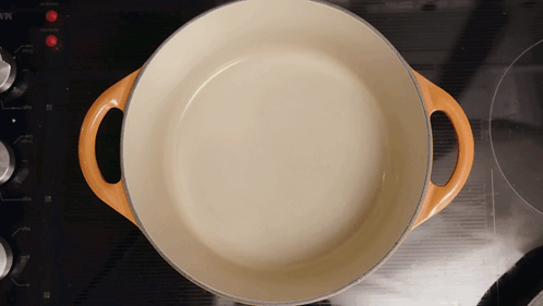 White Pot With Orange Handles On Stove GIF