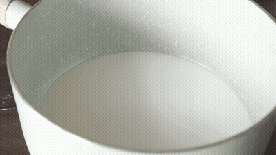 White Pot With Wooden Handle Filled With Milk GIF