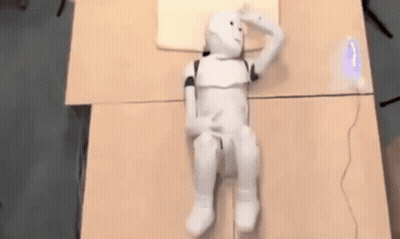 White Robot Laying On Table With Pillow GIF