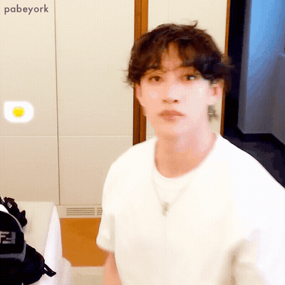 White Shirt Man With Necklace Looks At Camera GIF
