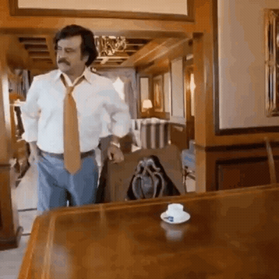 White Shirt Tie Man By Wooden Table With Cup GIF