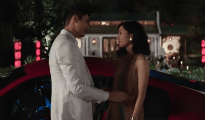 White Suit Man and Brown Dress Woman Holding Hands Red Car