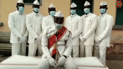 White Suited Men With Masks Around White Coffin GIF