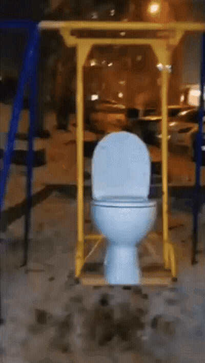 White Toilet Hanging From Yellow Pole In Playground GIF