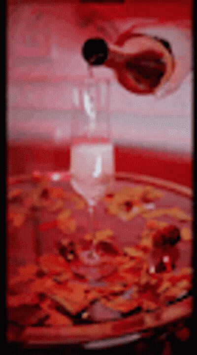 Wine Being Poured Into Glass On Tray With Flowers GIF