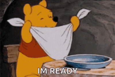 Winnie The Pooh Is Sitting At A Table With A Towel Around His Neck And A Bowl Of Water . GIF