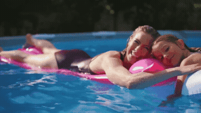 Woman And Child Laying On Rafts In Pool GIF