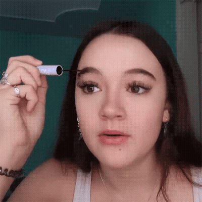 Woman Applying Mascara To Eyebrows In White Tank Top GIF