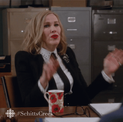 Woman At Desk With Coffee And Schitts Creek Logo GIF