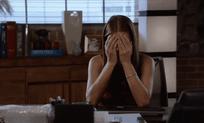 Woman At Desk With Hands On Face In Front Of Obstetrics Book GIF