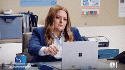 Woman At Desk With Laptop And Superstore Mug GIF
