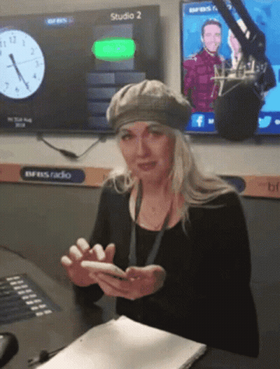 Woman At Desk With Phone In Front Of Studio 2 Screen GIF