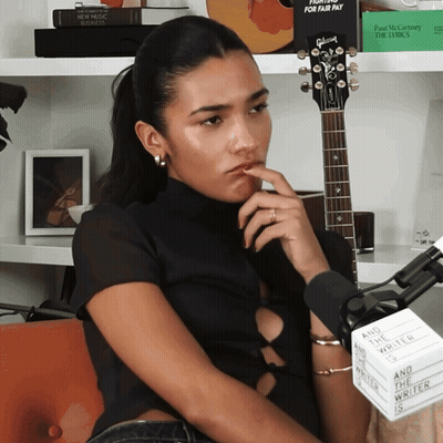 Woman At Microphone With Sign And The Writer Is GIF