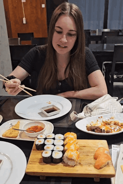 Woman At Table With Chopsticks And Sushi GIF