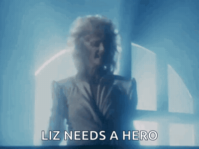 Woman At Window Saying Liz Needs A Hero GIF
