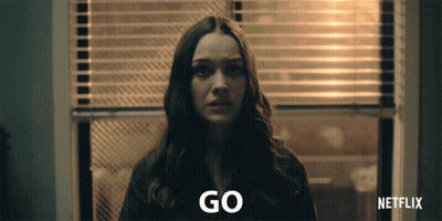 Woman At Window With Blinds Saying Go GIF