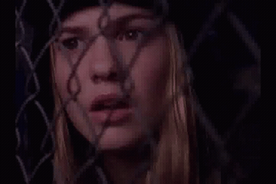 Woman Behind Chain Link Fence Looking Through GIF
