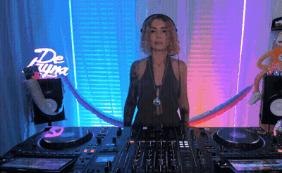 Woman Behind DJ Mixer In Front Of De Luna Neon Sign GIF