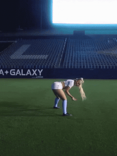 Woman Bending Over on Soccer Field With Galaxy Sign