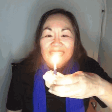 Woman Blowing Birthday Candle On Cupcake