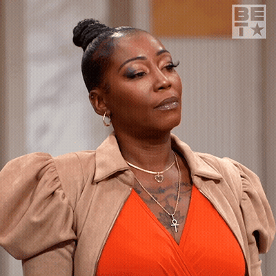 Woman Brown Jacket Orange Top Ankh Necklace GIF