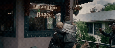 Woman Carrying Baby In Front Of Maggie's Diner GIF