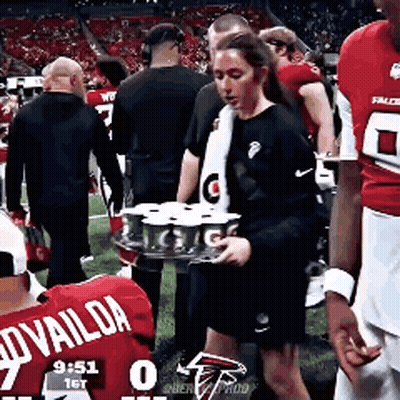 Woman Carrying Tray Of Cans On Football Field GIF