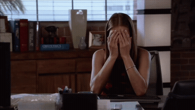 Woman Covering Face At Desk With Obstetrics Book GIF