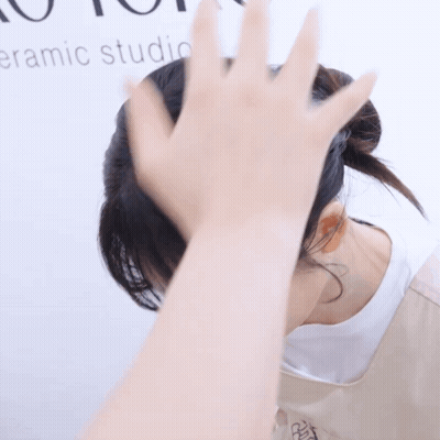 Woman Covering Face Beside Ceramic Studio Sign GIF