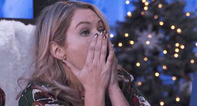 Woman Covering Mouth With Hands At Christmas Tree GIF