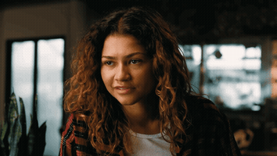 Woman Curly Hair Plaid Shirt Looks At Camera GIF